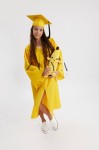 Adult graduate in elegant yellow gown against academic backdrop