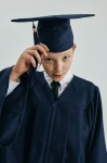 Navy graduation gown on young scholar in Dublin ceremony – elegant navy fabric with golden tassel cap