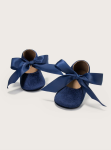 Navy velvet baby shoes with satin bow on white background