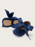 Close up of satin bow on navy velvet infant booties