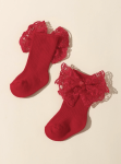 Close-up of red lace bow on baby socks showing floral detail