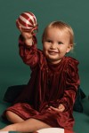 Girl wearing burgundy velour party dress with ruffle shoulders