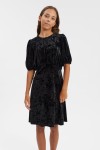 Girl wearing black velvet Clara dress with puff sleeves and bow back