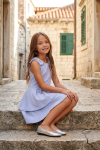 Harper light blue dress for girls – styled outdoors, seated pose