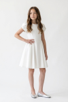 Rumi white flared dress for girls – hand on hip, front view