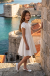 Rumi white dress for girls with tulip sleeves – outdoors by a stone wall