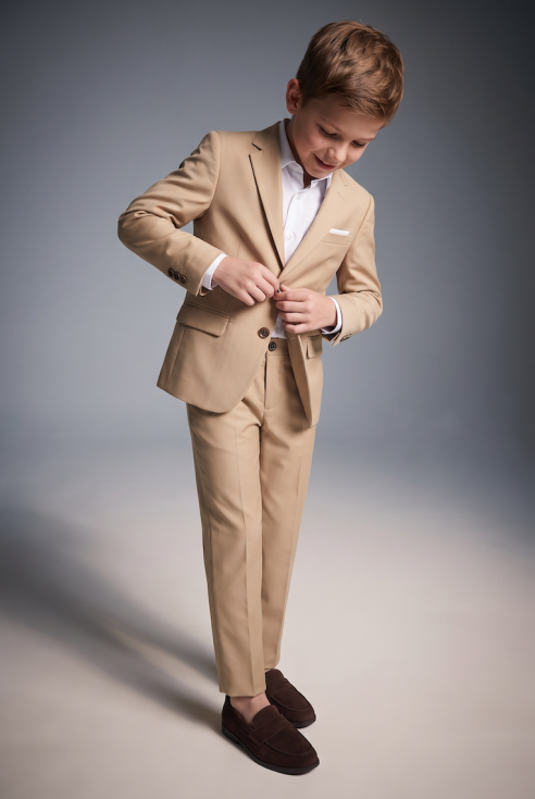 Liam beige suit for boys – blazer and trousers, boy buttoning the blazer, front view