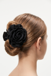 Black flower claw clip for girls holding a low bun – back view