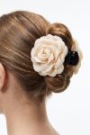 Beige fabric flower claw clip for girls holding a bun – back view