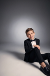 Sam black suit for boys with bow tie – boy sitting on the floor, front view